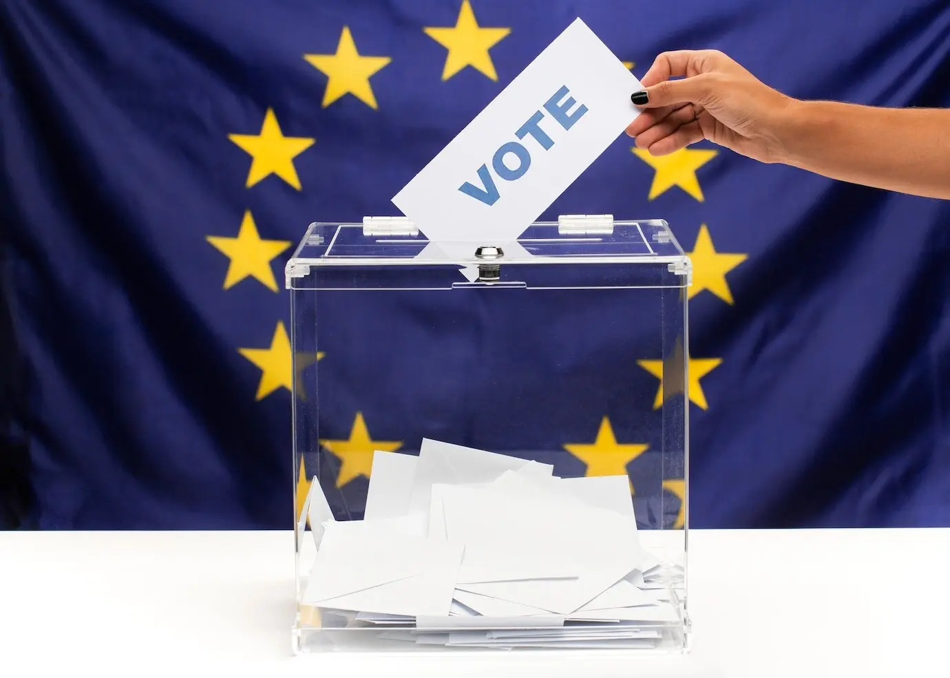 Бюллетень, удерживаемый рукой, опускается в избирательную урну.